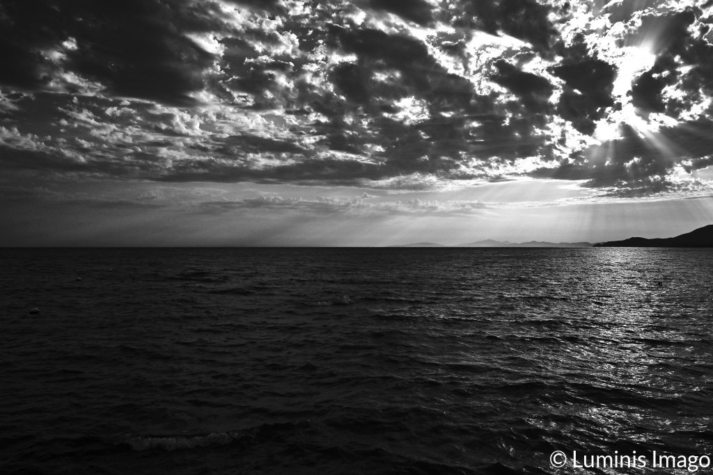 A black and white photographs of a dramatic sunset over the dark sea